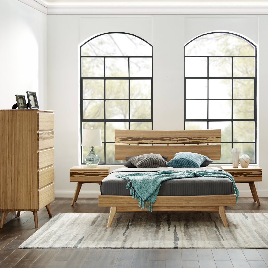 A renewable Azara Bamboo Bedframe by Greenington in caramel color, placed in a bedroom with a five-layer drawer next to it.