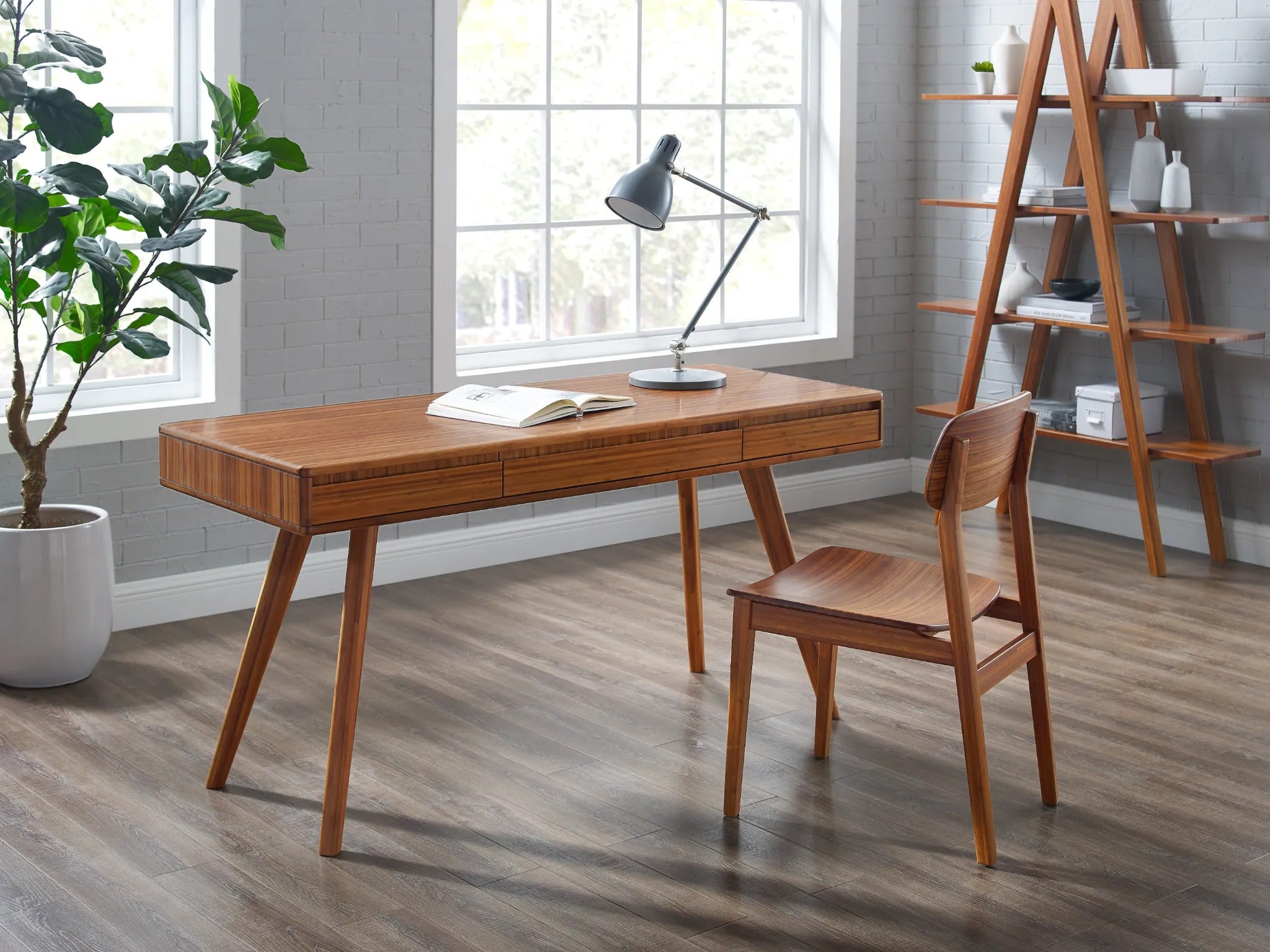 A renewable Currant Bamboo Writing Desk by Greenington in amber color, placed in an office room.