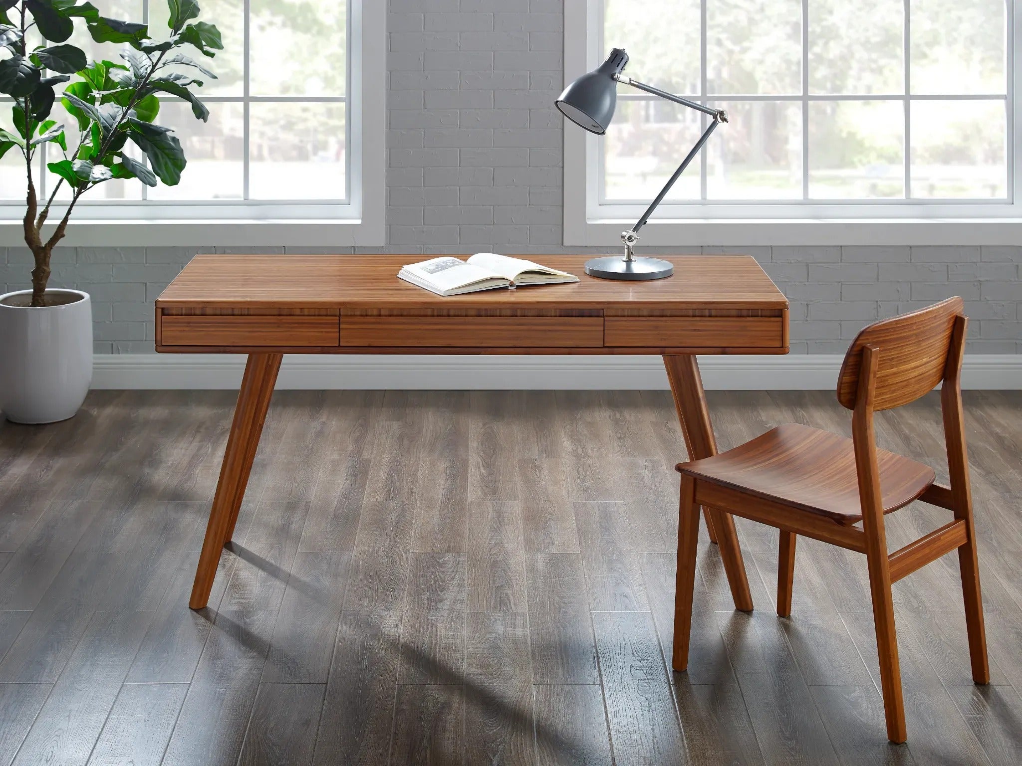 A renewable Currant Bamboo Writing Desk by Greenington in amber color, in an home office setting.