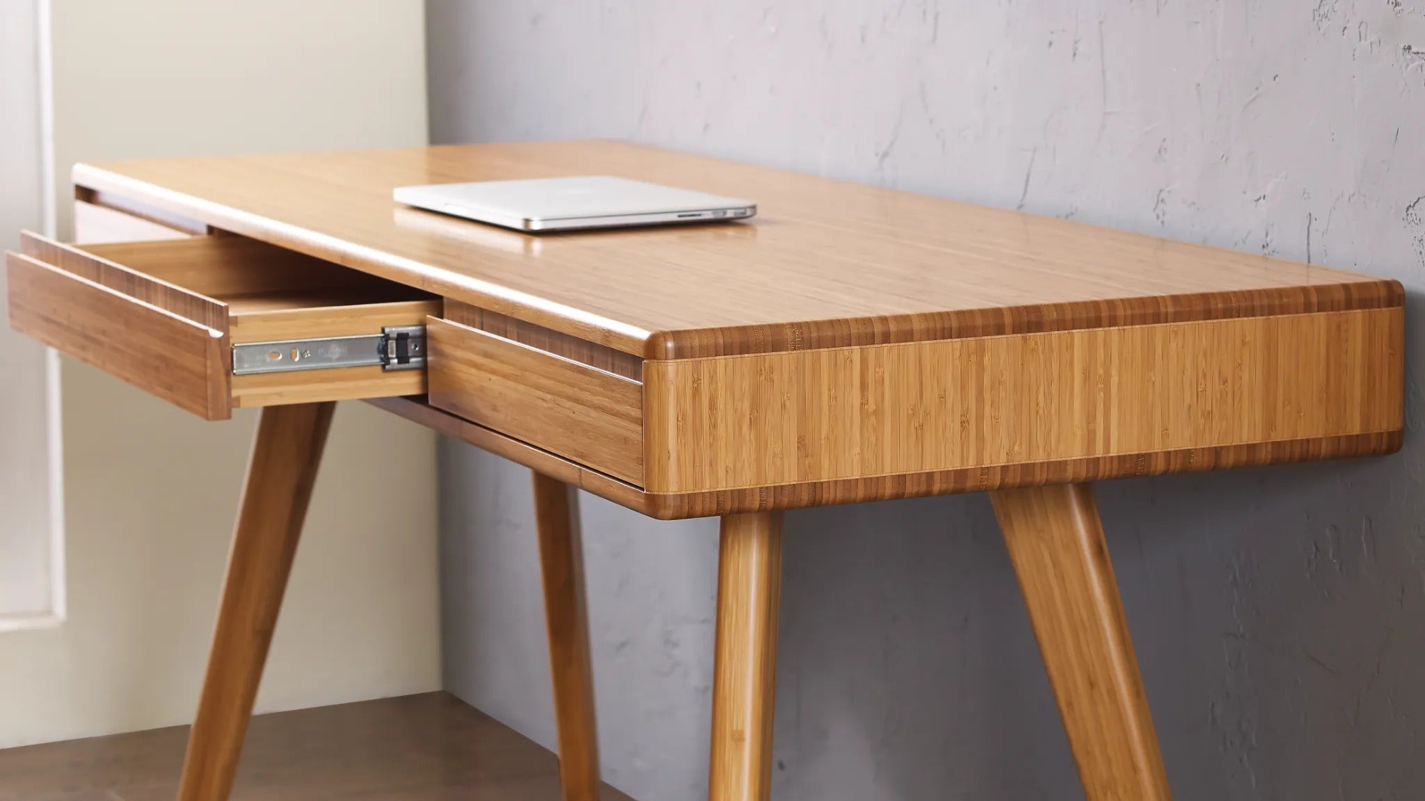 A renewable Currant Bamboo Writing Desk by Greenington in caramel color, with a detailed view of the drawer's dovetail joints.