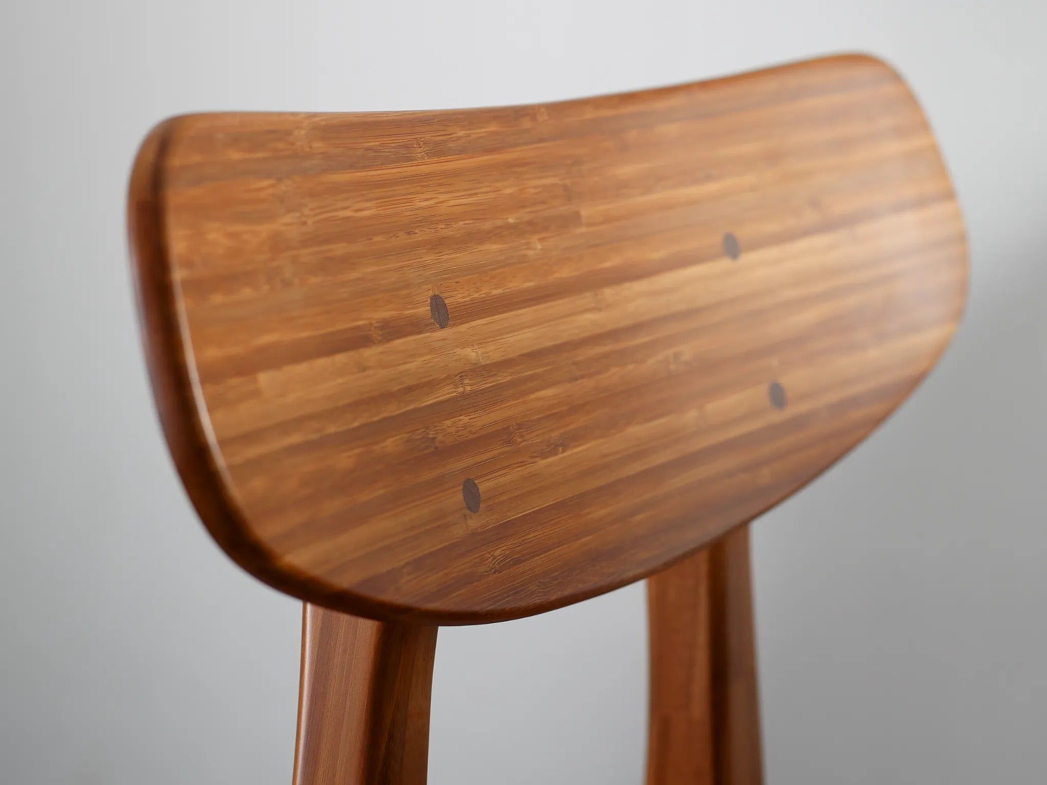 A renewable Cassia Bamboo Dining Chair by Greenington in amber color, detailed view of the backrest.